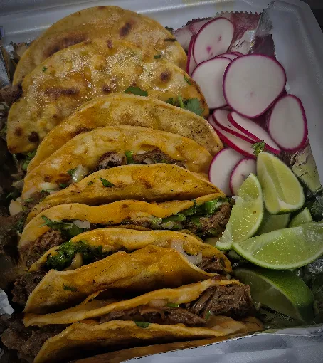 Tray of birria tacos and mulitas with radish and lime wedges